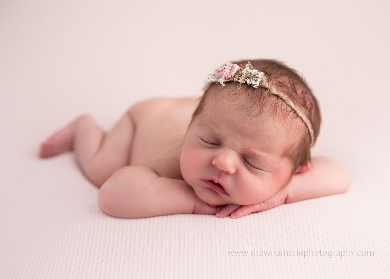 Newborn Alivia posed on table with chin on hands and delicate headband _ Greenfield Indiana newborn photography